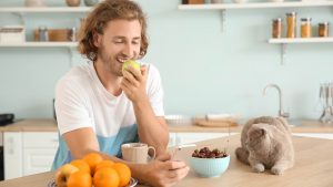 Padrone che mangia la frutta con gatto accanto